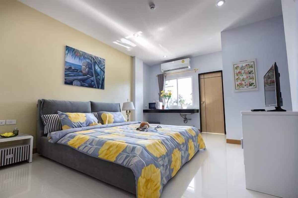 A bedroom with a bed, bedside table, lamp, and artwork on the wall.