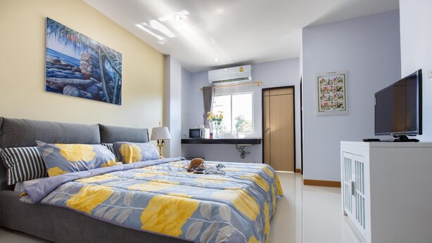 A bedroom with a bed, a TV, a desk, and a window.