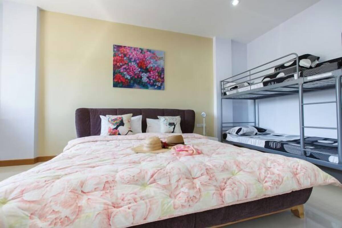 A bedroom with a bunk bed, a floral bedspread, and a painting on the wall.