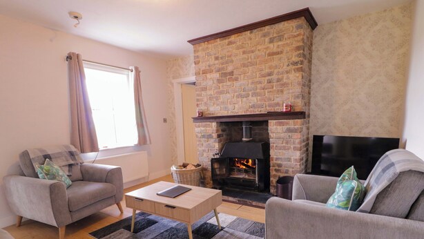 A living room with a fireplace, two sofas, a coffee table, and a television. - Molly's Cottage (Enniskillen)