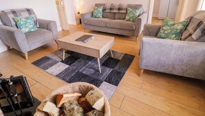 A living room with two grey sofas, a wooden coffee table, and a black and grey rug. - Molly's Cottage (Enniskillen)