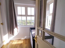 A room with a wooden floor, a window with curtains, and a door with a brass handle.