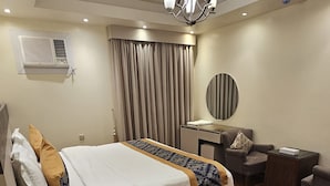 A hotel room with a bed, a desk, a chair, a mirror, and a ceiling fan. - Abha lamar for serviced apartments (Riyadh)