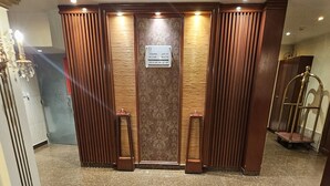 A reception area with a marble floor, wooden paneling, and a sign above the door. - Abha lamar for serviced apartments (Riyadh)
