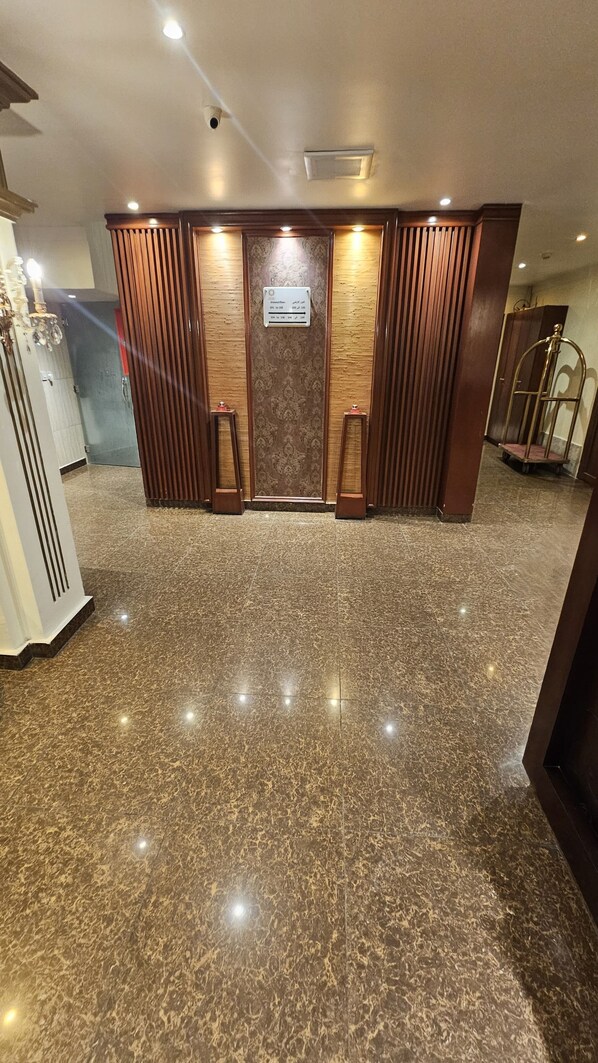 A reception area with a marble floor, wooden paneling, and a sign above the door. - Abha lamar for serviced apartments (Riyadh)