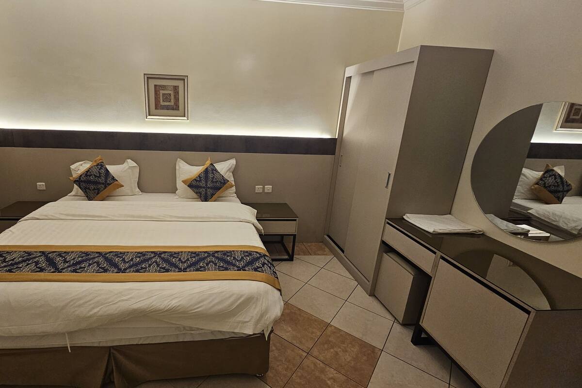 Ein Hotelzimmer mit einem großen Bett, einem Nachttisch, einem Spiegel und einem Kleiderschrank.