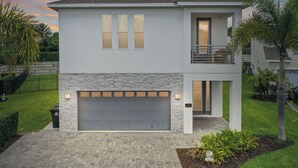 A two-story house with a garage, a balcony, and a stone facade.