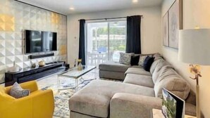 A modern living room with a sectional sofa, a yellow armchair, a flat-screen TV, and a glass coffee table.