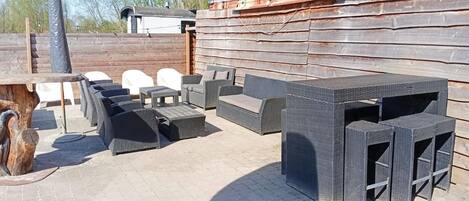An outdoor patio area with wicker furniture, including sofas and tables, and a wooden table.