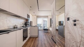 Een moderne keuken met een centraal eiland, een ingebouwde oven en uitzicht op de woonkamer.