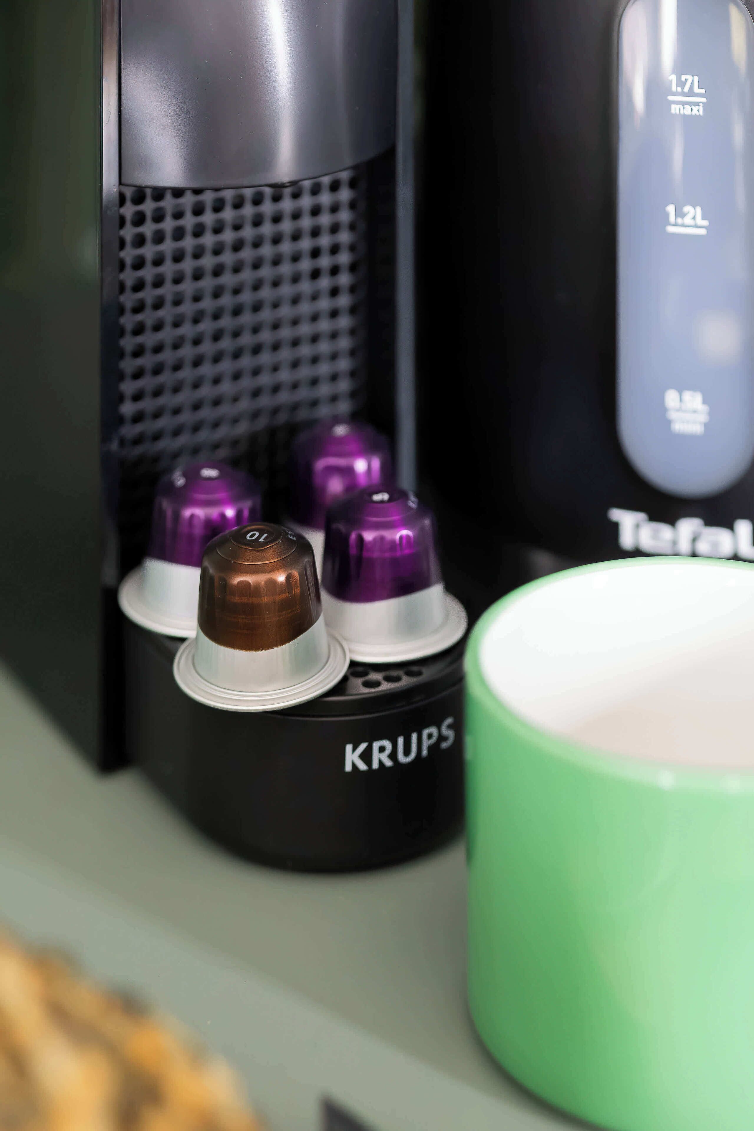 Uma máquina de café com quatro xícaras, sendo uma delas cheia.