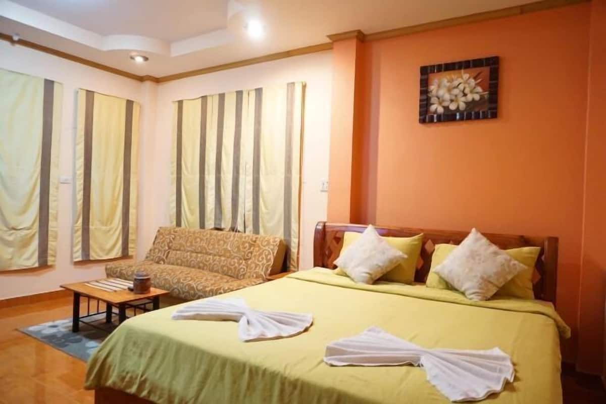 A hotel room with a bed, a sofa, and a small table.