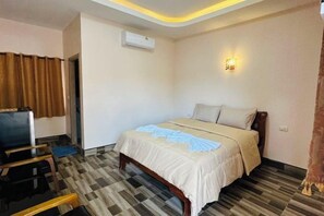 A hotel room with a bed, a desk, and an air conditioning unit. - Bussaba Resort Home (Rayong)
