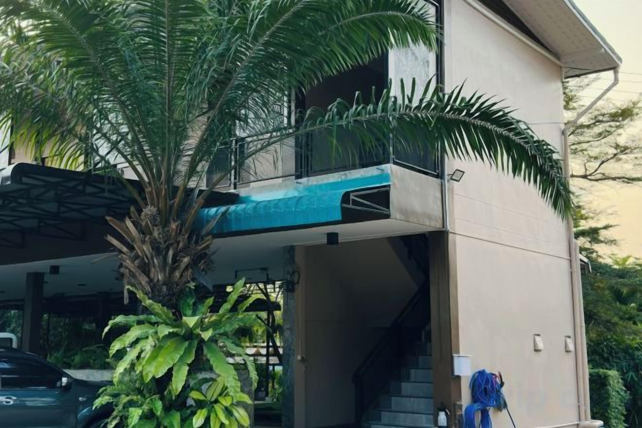 A modern two-story building with a balcony, a staircase, and a palm tree.