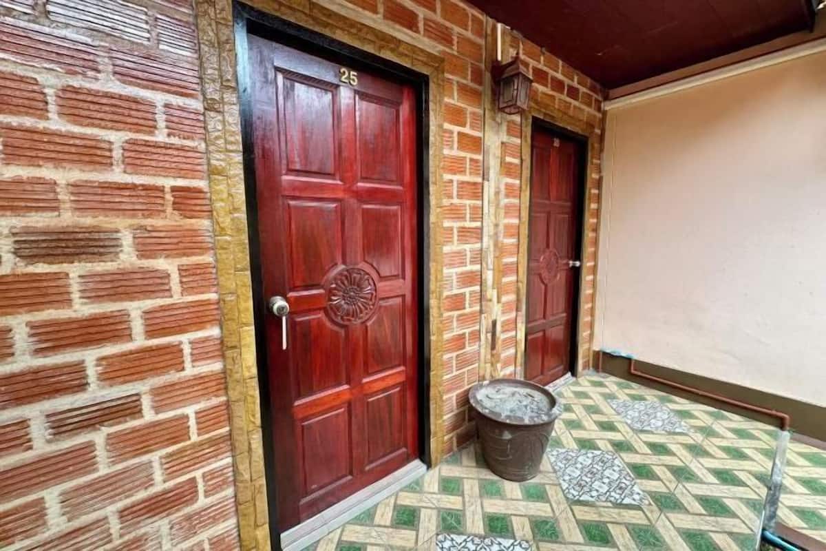A brick wall with two red doors, numbered 25, and a tiled floor with a geometric pattern.