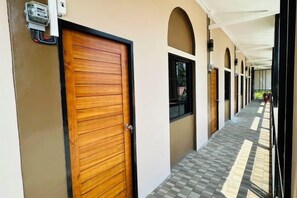 A corridor with a wooden door, arched windows, and a tiled floor. - Bussaba Resort Home (Rayong)