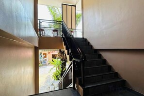 A staircase leading to an outdoor area with a view of a street and some greenery. - Bussaba Resort Home (Rayong)
