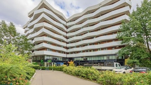 Ein mehrstöckiges Gebäude mit einem Zickzack-Design, mit Balkonen und einem zentralen Innenhof mit Grünflächen.
