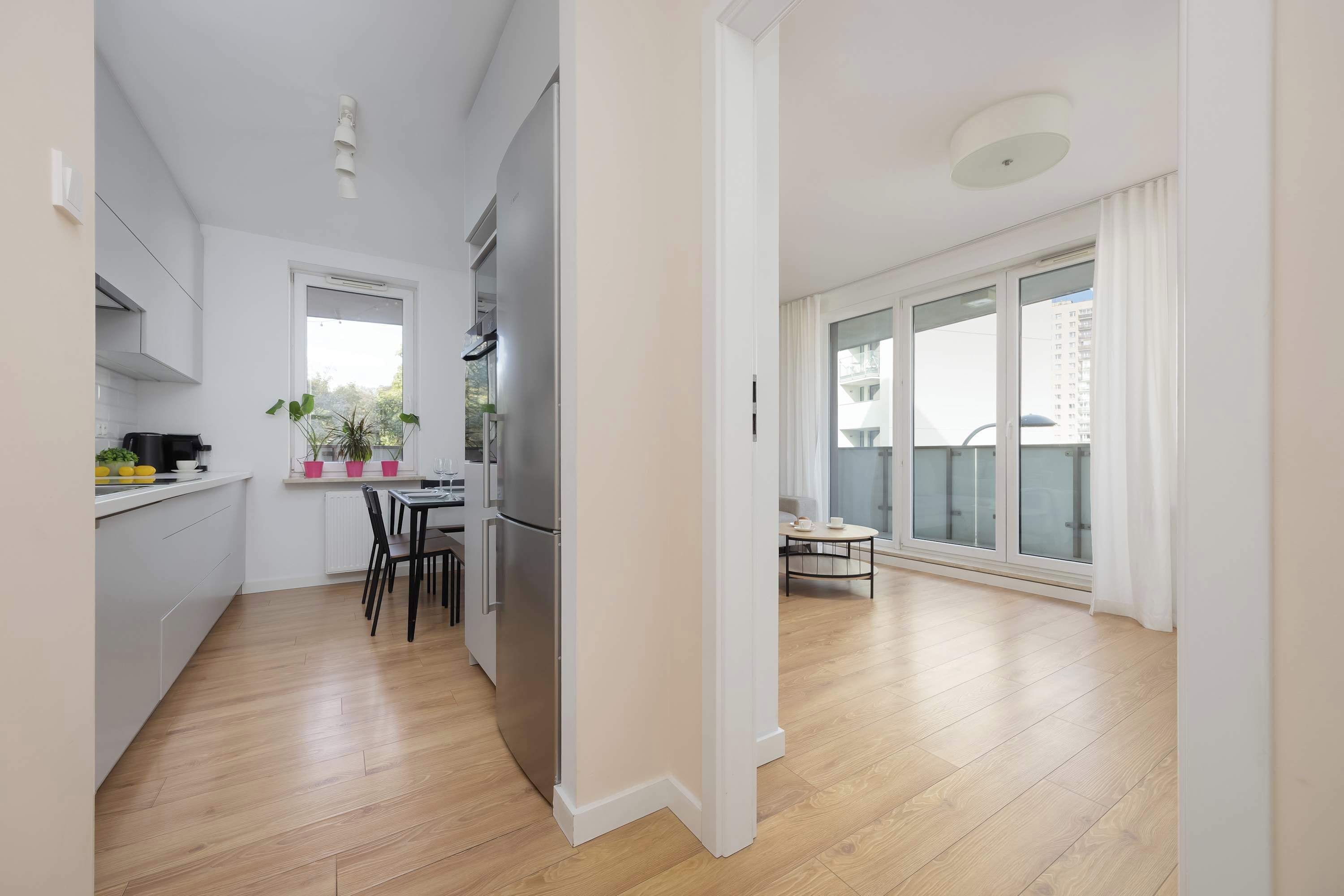 A modern apartment with a kitchen, dining area, and large sliding glass doors to a balcony.