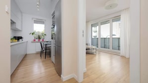 Ein modernes Apartment mit Küche, Essbereich und großen Schiebeglastüren zum Balkon.