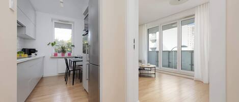 A modern apartment with a kitchen, dining area, and large sliding glass doors to a balcony.