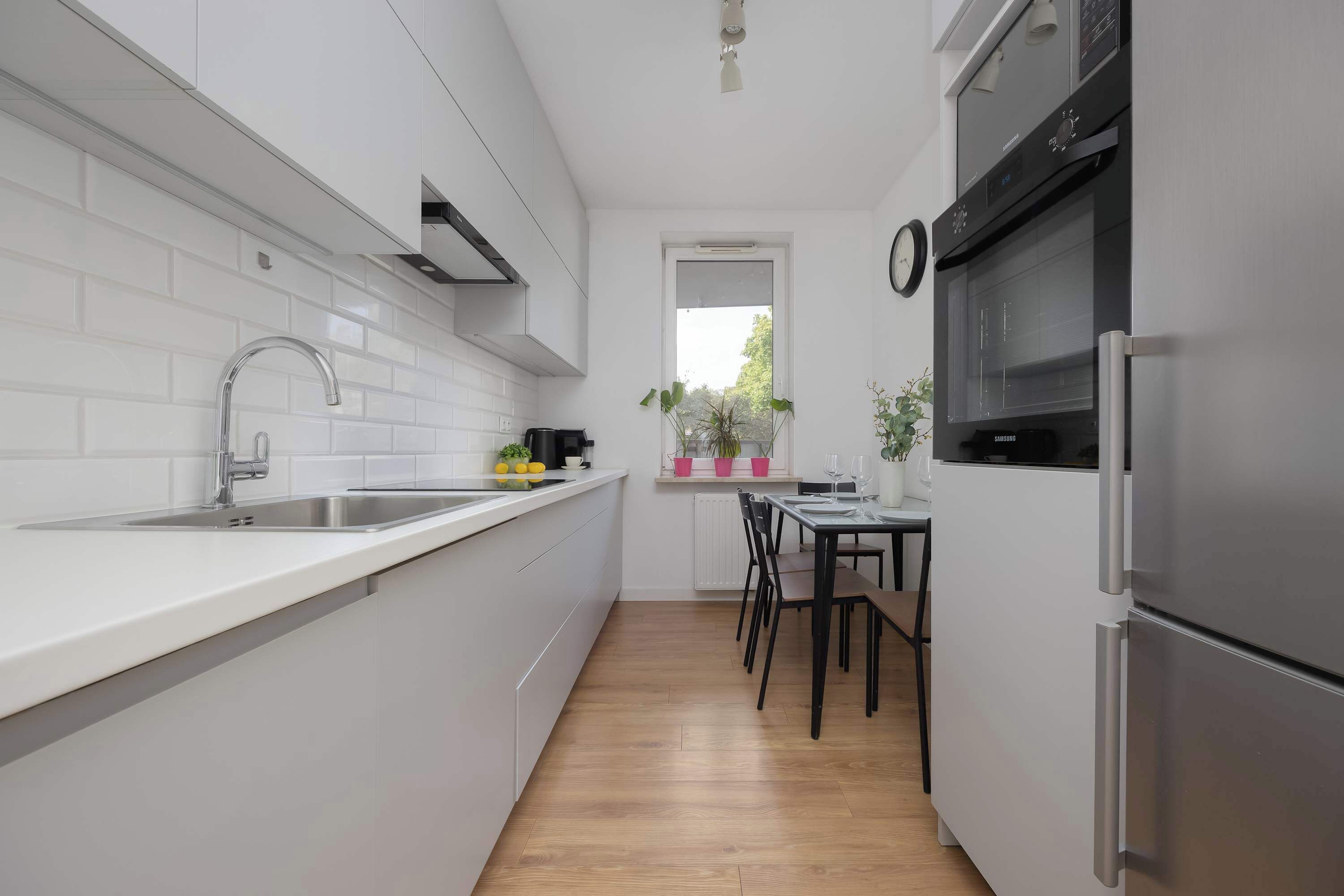 A modern kitchen with white cabinetry, a stainless steel sink, and a built-in oven.