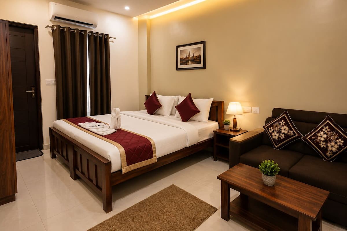 A hotel room with a bed, a sofa, a nightstand, a lamp, a picture on the wall, and a door with curtains.