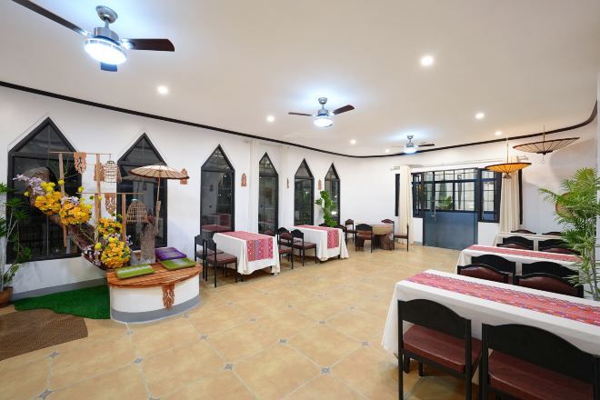 Un restaurante con mesas, sillas, ventiladores de techo y plantas decorativas.