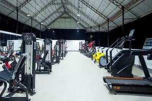 A gym with various exercise equipment including treadmills, weight machines, and a rowing machine. - Fu Er Man Hotel (Luang Prabang)