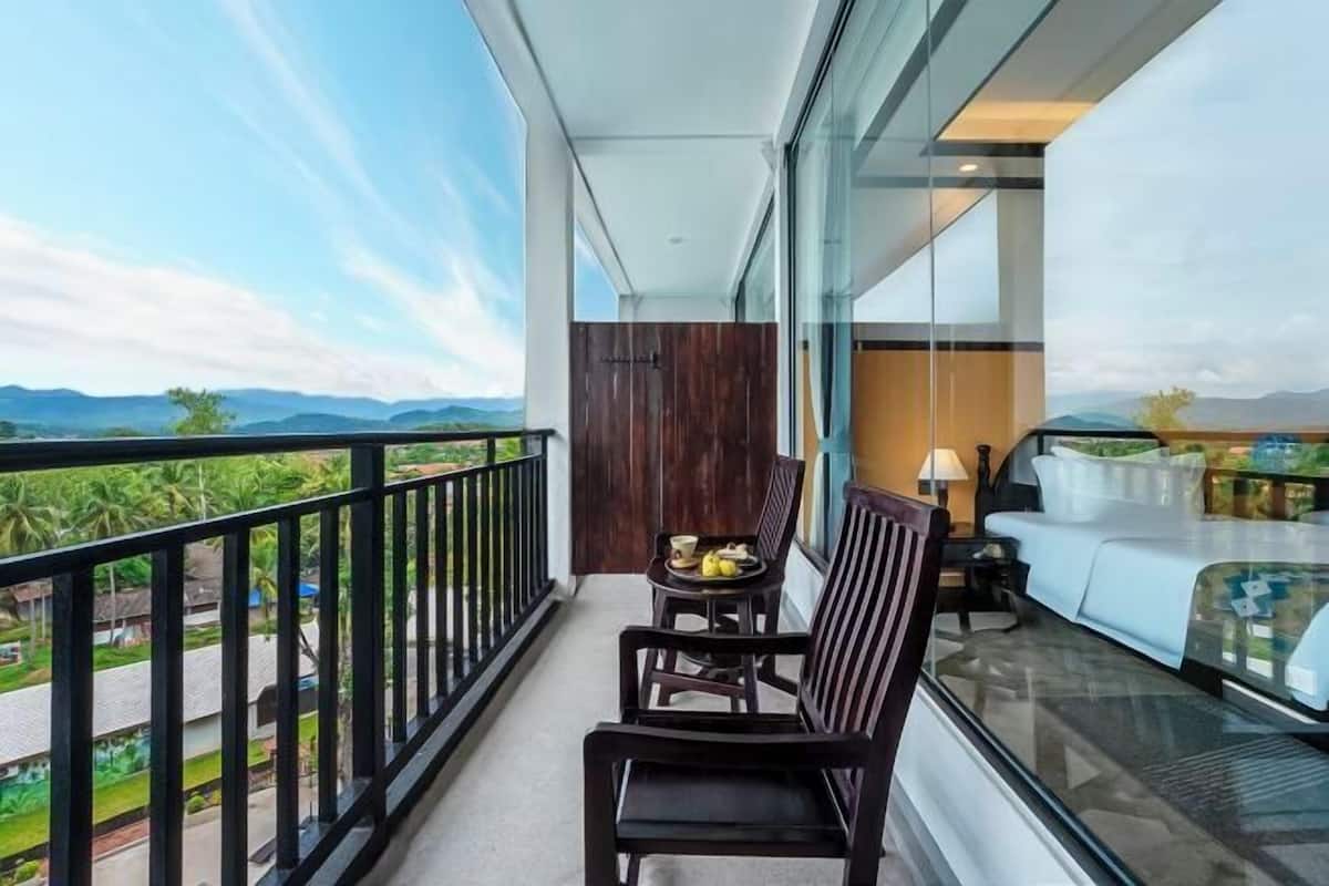A balcony with a table and chairs, a sofa, and a view of the landscape.