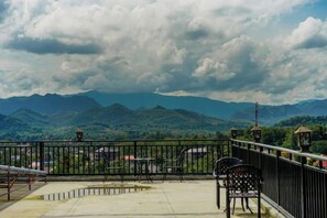 A balcony with a view of green mountains, a railing, and a few chairs. - Fu Er Man Hotel (Luang Prabang)
