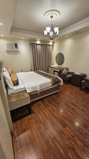 A hotel room with a bed, a desk, a chair, a mirror, and a ceiling fan. - Saad Palace for seviced apartments (Abha)