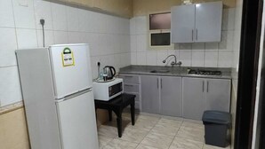 A compact kitchen with a refrigerator, microwave, sink, and cabinets. - Saad Palace for seviced apartments (Abha)