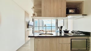 Une cuisine moderne dotée d’un grand îlot central, d’un four à micro-ondes encastré et offrant une vue sur la ville.