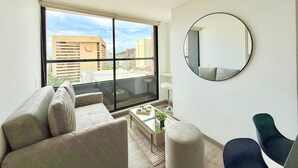 Un salon moderne avec une grande fenêtre, un miroir rond et un canapé.