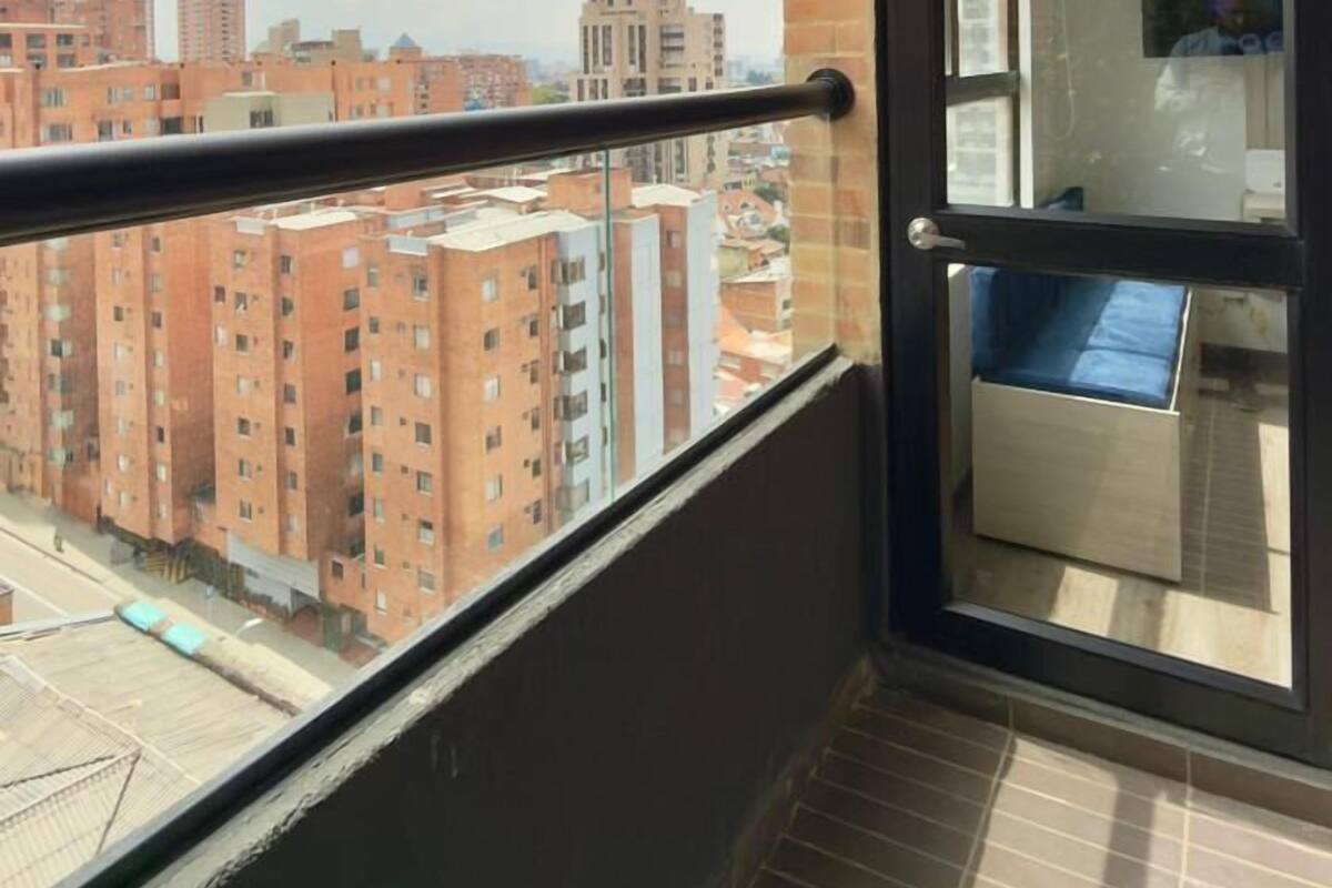 Un balcon offrant une vue sur le paysage urbain, avec des gratte-ciel et un ciel dégagé.