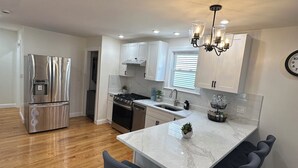 A modern kitchen with a central island, built-in appliances, and a dining area with bar stools. - Modern Brand New Dorchester Apartment! Quiet, Convenient & Minutes from Boston! (Dorchester)