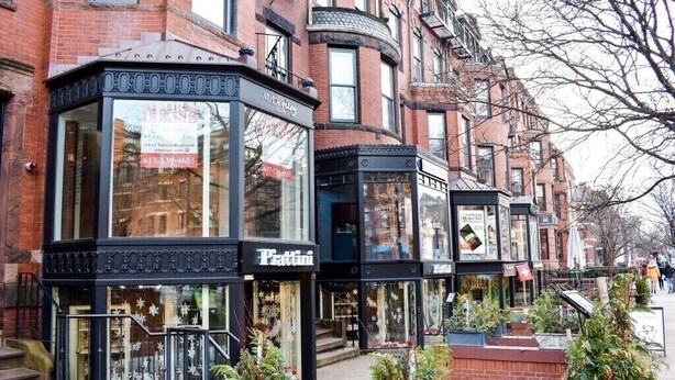 A row of brick buildings with storefronts, including a visible 'Pettini' store. - Modern Brand New Dorchester Apartment! Quiet, Convenient & Minutes from Boston! (Dorchester)