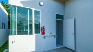 Un edificio moderno con un extintor en la pared, una puerta y una ventana con persianas.