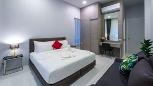 Una habitación de hotel moderna con una cama grande, un escritorio y un sofá.