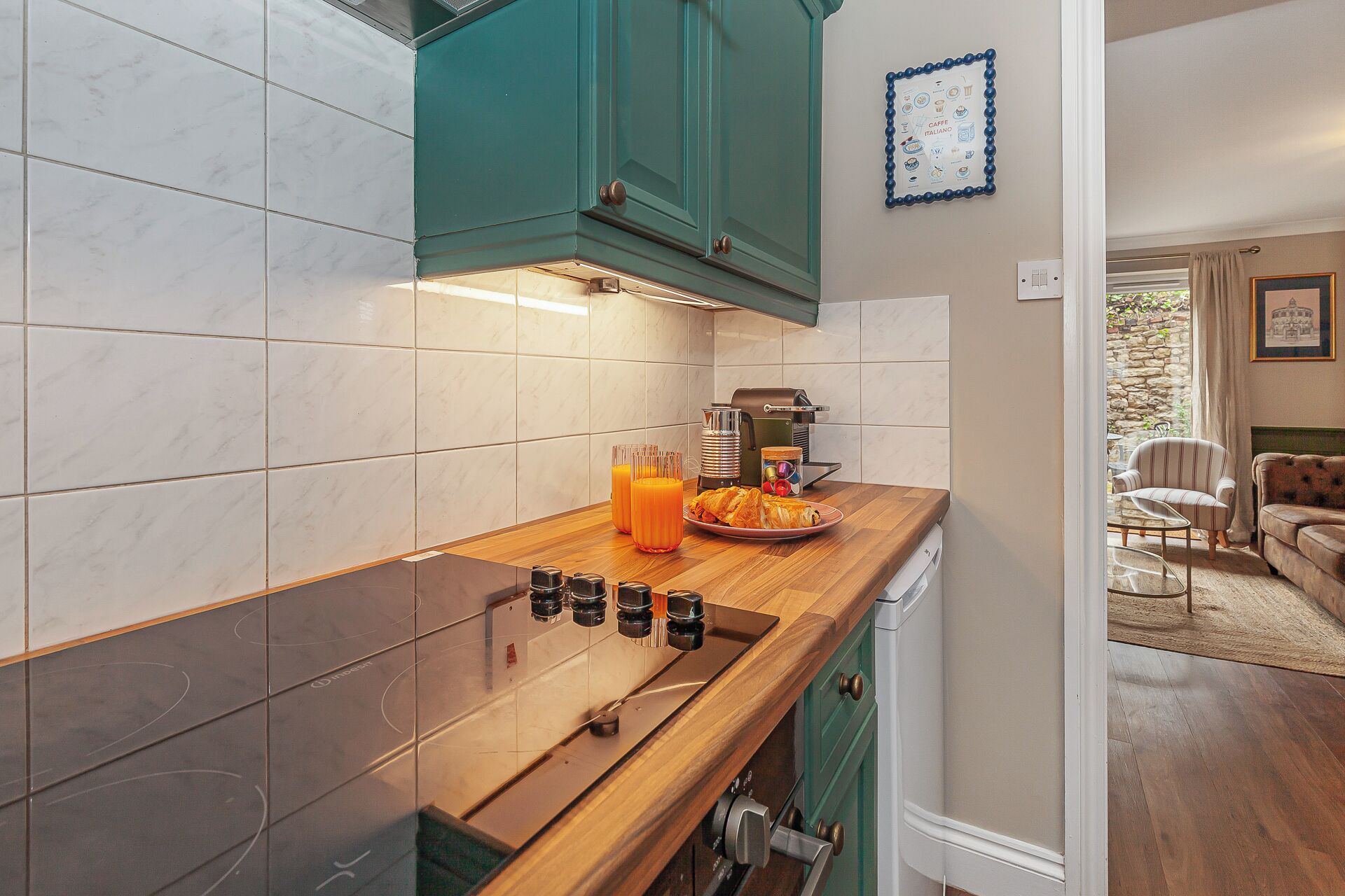 A modern kitchen with a wooden countertop, a coffee machine, and a breakfast plate with croissants and orange juice.