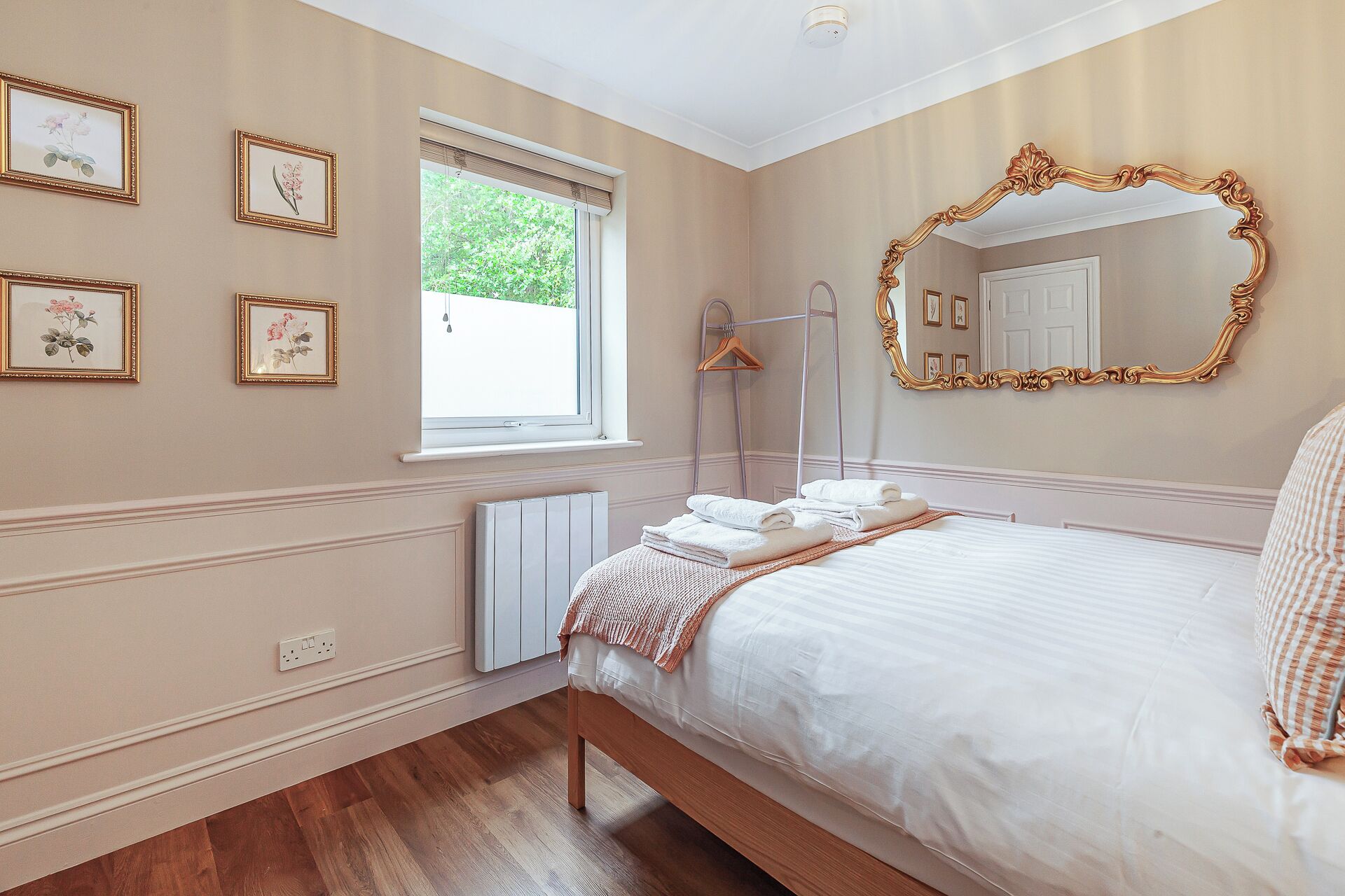 Een slaapkamer met een bed, een grote spiegel en ingelijste foto's aan de muur.