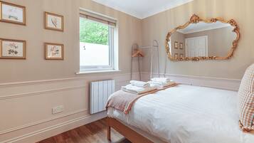 Een slaapkamer met een bed, een grote spiegel en ingelijste foto's aan de muur.