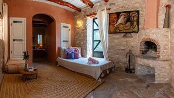 Una camera da letto rustica con un camino in pietra, un letto con cuscini e un quadro appeso al muro.