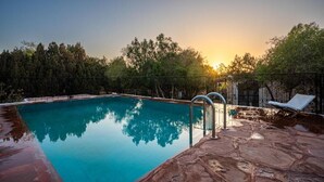 A swimming pool with clear water, surrounded by a stone deck and metal railings. - Atlantis 12 Maison d’hôtes et d’art (Ounagha)