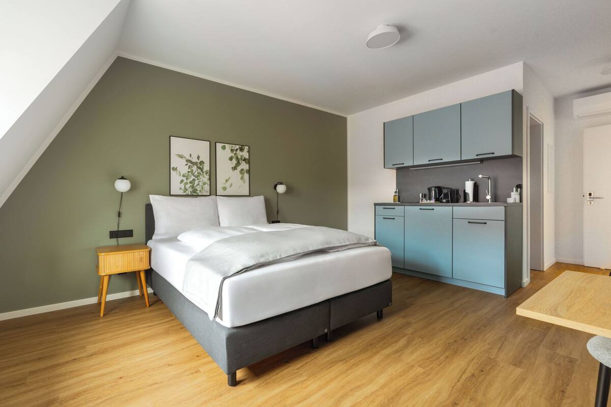 Una camera da letto con un letto, comodini, una scrivania e un angolo cottura.