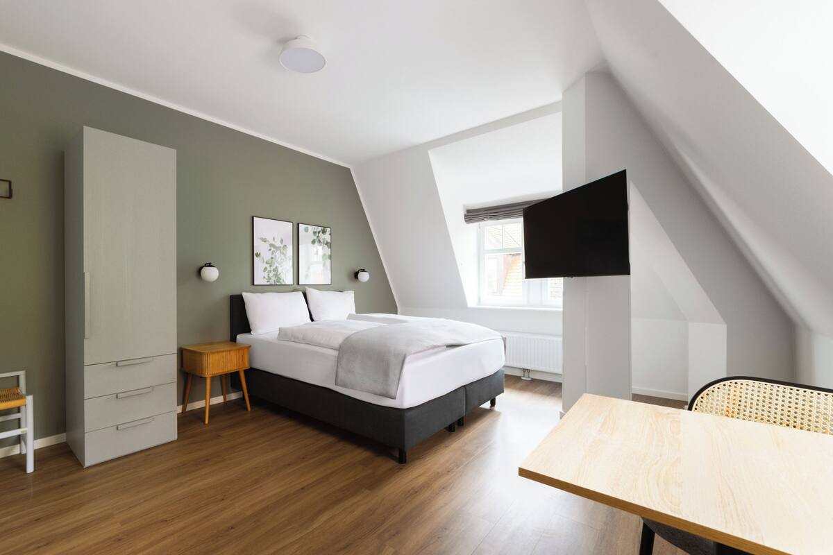 Una camera da letto moderna con un letto, un comodino e una scrivania.