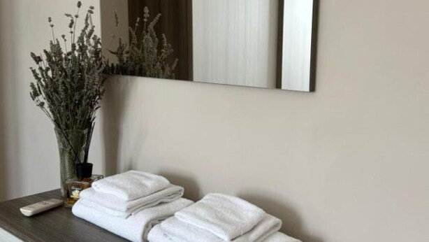 A bathroom with a mirror, a vase with dried flowers, and neatly folded towels on a wooden counter. - Tourist Location A Casa di Viola: 1 Bedroom House (Orvieto)