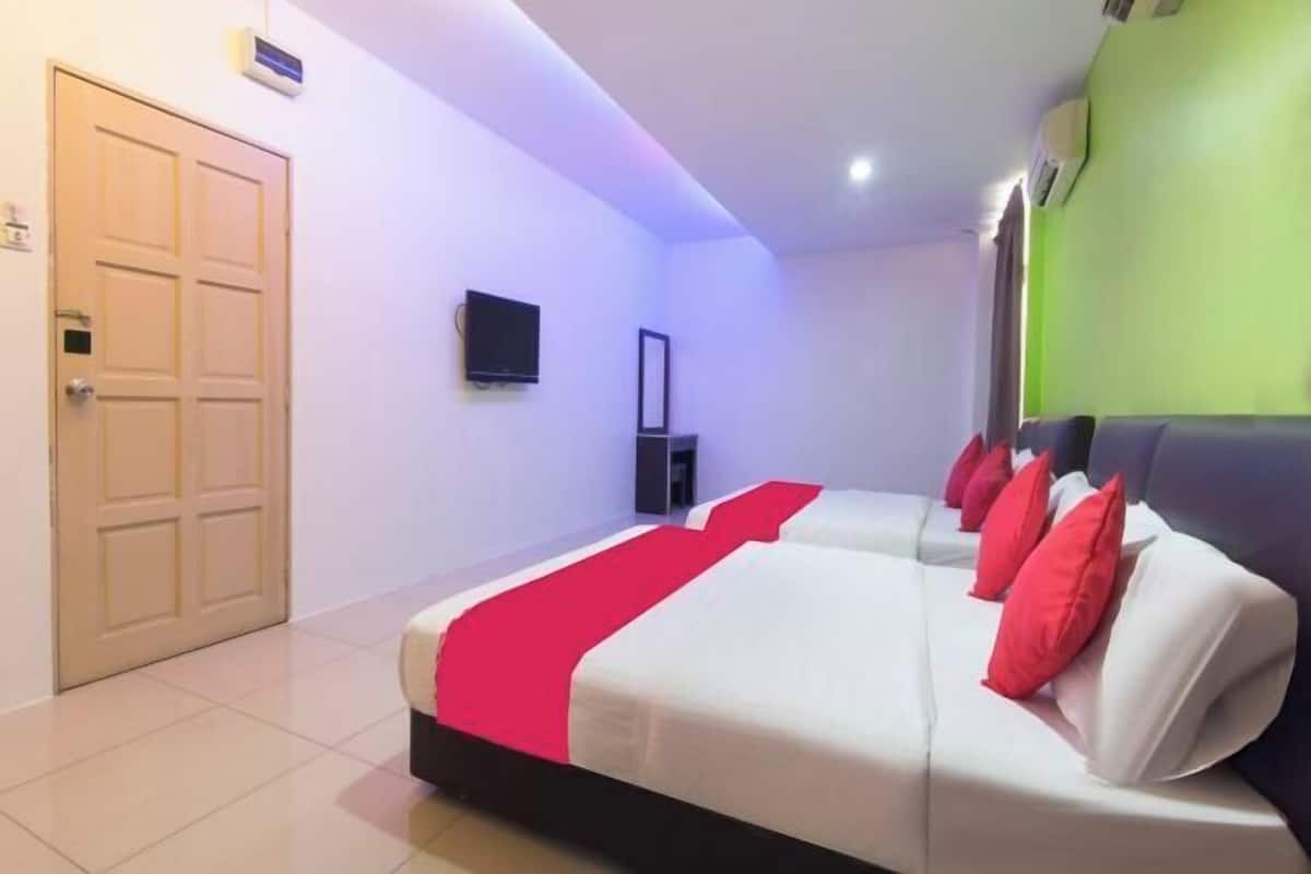 Ein Hotelzimmer mit Bett, Fernseher, Tür und einer grünen Wand.
