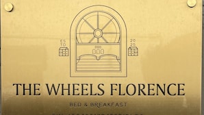 A brass plaque with a bed and breakfast logo, "THE WHEELS FLORENCE," and a CIN code. - The Wheels Florence Bed&Breakfast Superior Bedroom MENTA (Florence)